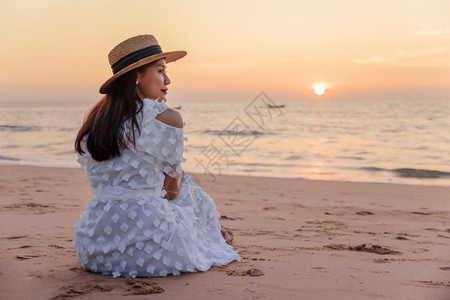 关心身体拉丁海滩上快乐的亚洲年轻女子看着摄影机在日落背景下旅行度假暑图片