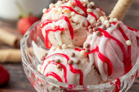 一种甜的夏天草莓香蕉和奶油罗马人冰淇淋在玻璃碗里加红酱图片