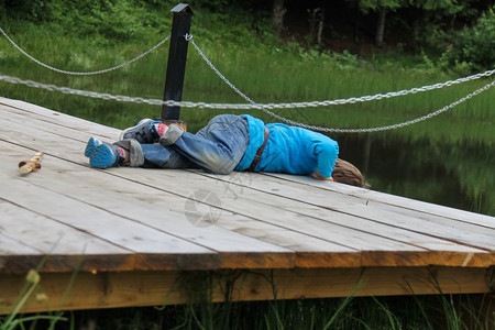 农村绿色田园诗般的男孩躺在湖边木桥上图片