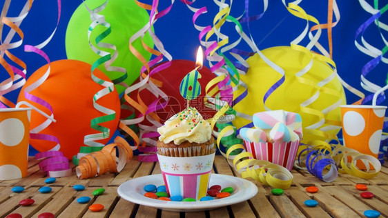 奶油食物幸福生日6小蛋糕在乡村木桌上燃烧着蜡烛背景是彩色气球塑料杯和糖果背景是蓝色派对墙背景图片