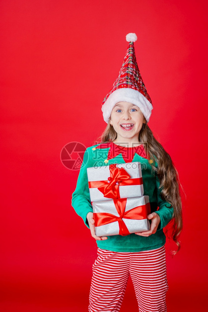 带礼物的精灵女孩亮红色背景上的圣诞老人助手一个美丽的精灵婴儿肖像复制空间带礼物的精灵女孩亮红色背景上的圣诞老人助手假期矮有色图片