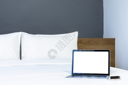 在旅馆卧室内背景工作和业余休闲以及度假旅行概念下的中用空白屏幕和智能电话在白色床上装饰的手提笔式电脑带有智能手机工作区奢华联系图片