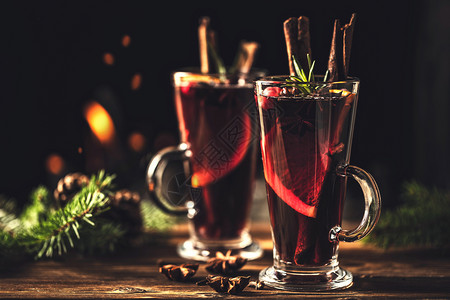 熟料在火炉灾的背景下在圣诞节假日传统冬季饮酒时木制桌上的边装有玻璃杯中调味品的混合葡萄酒橙祝贺图片