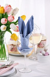 早午餐奶油烘烤一张巾纸折成兔子耳朵的玻璃杯即为纪念复活节而设置一个喜宴会桌的概念图片