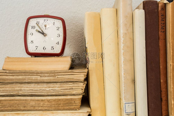 木制架子上的旧书和小时钟在小时钟木制架上学习收藏术的图片