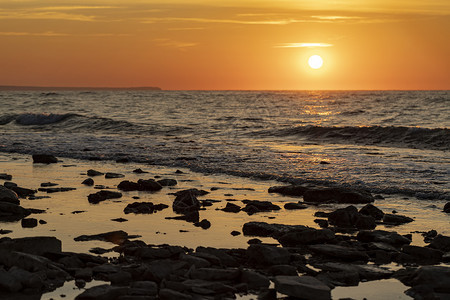 太阳和石头在水面上闪耀着海景的清晨惊人岩石海岸图片