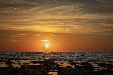 太阳和石头在水面上闪耀着海景的清晨夏天日出复制图片