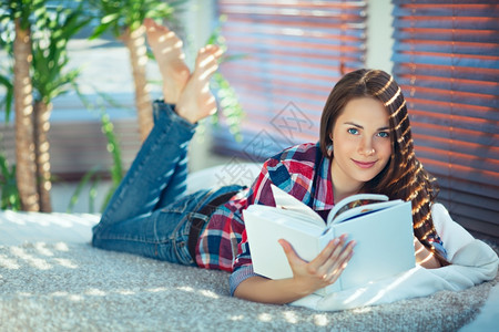 年轻美女躺在肚子上看书躺在肚子上学生阅读肖像图片