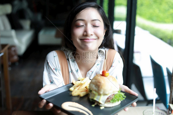 快乐的亚裔妇女微笑和快乐享受在咖啡和餐馆吃汉堡包的放松时间享受着脸饮食图片