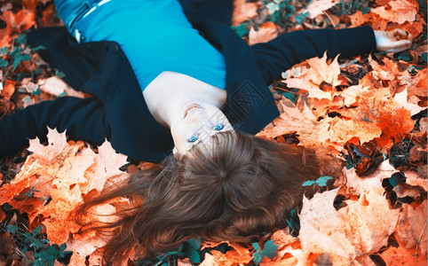 落下快乐的笑女孩躺在秋叶树上肖像手图片