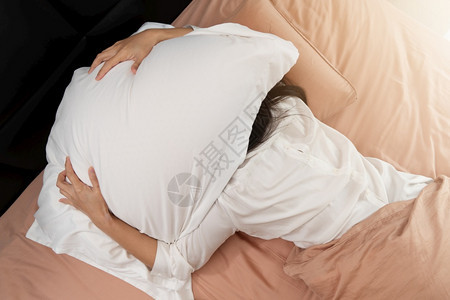 就寝时间钟睡不着的女人躲在枕头底下讨厌早上醒来的晨疲劳图片