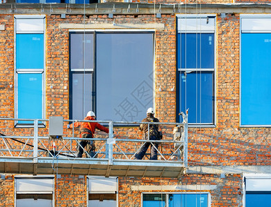 轮廓工作施现场用摇篮和铝剖面图在正建造的房屋表面安装大型窗户的建筑工用大窗户这是节省房屋热量的一个概念即利用绞盘和移动平台翻修房图片