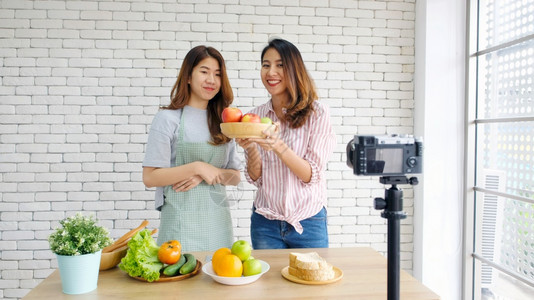 技术两位年轻的青女食物博客在录制视频时交谈与快乐刻vlog概念人与科技通讯等水果图片