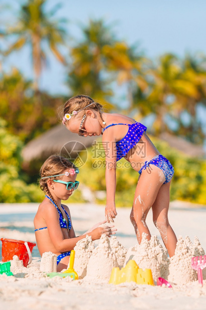 海岸可爱的小女孩在白色热带海滩上玩沙子两个孩做沙城堡在热带海滩玩得开心两个孩子在热带海滩造沙城堡洋滨图片