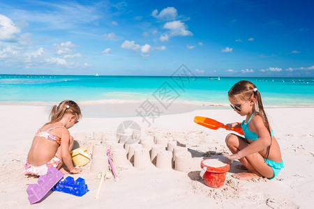 幸福两个孩子在热带海滩造沙城堡玩得开心的小孩在热带海滩上做沙城堡和玩乐童年享受图片