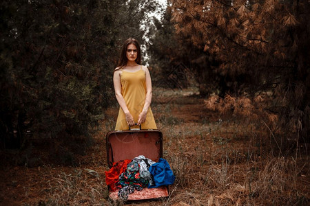 围巾一个穿着黄色礼服的年轻美女肖像站在雨中拿着一个穿落衣的开旧式手提箱摆姿势模型图片