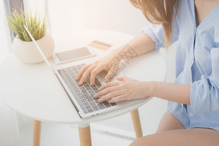 卡片夏天亚洲妇女在家中工作或网上购物时使用笔记本电脑的亚洲妇女手中在家里打字沟通图片