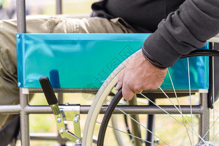 老年男人在公园穿黑红汗衫坐在轮椅上手麻痹的成年男子支持图片