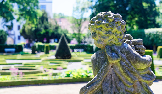 植物群自由度一个巴洛克天使的石头雕像在一个蓄意模糊的背景面前与一个巴洛克花园德国旅行图片