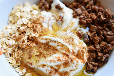 白色的一顿饭有机健康食品在梅斯利酸奶含巧克力的燕麦蜂蜜和肉桂白菜中吃早餐图片