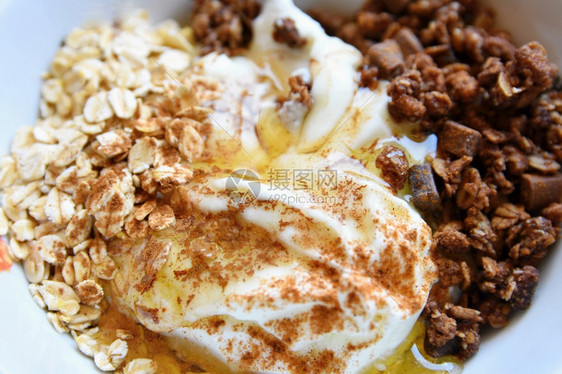 白色的一顿饭有机健康食品在梅斯利酸奶含巧克力的燕麦蜂蜜和肉桂白菜中吃早餐图片
