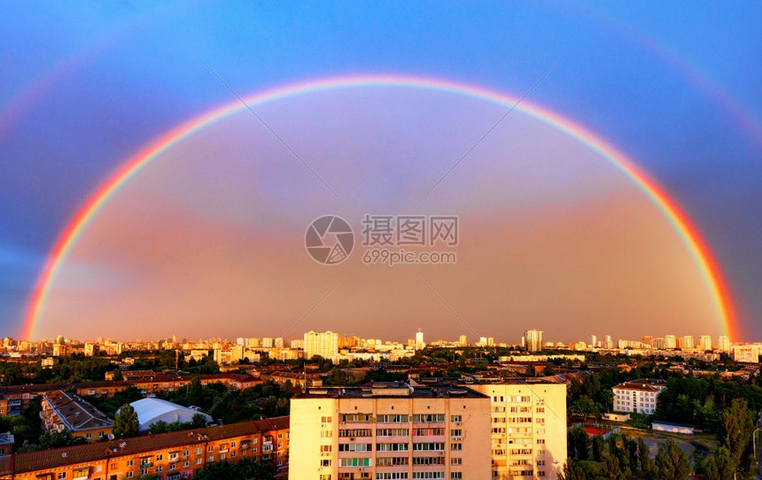 彩虹色棱镜城市住宅区全景和巨大的彩虹在夜空中的背景下太阳照亮了巨大彩虹在夜天空的晚城市风景中屋图片