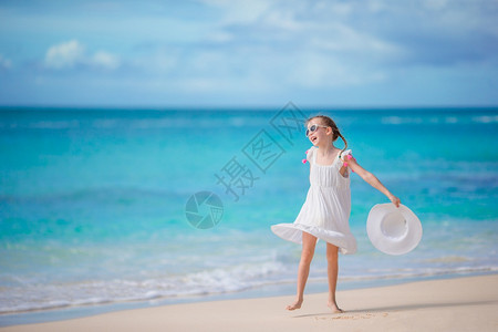 海岸线有趣的情感在海滩上穿着衣服的漂亮女孩快乐享受暑假背景蓝天和海中绿水在卡利比恩岛海边穿着洋装的漂亮女孩在海滩玩得开心图片