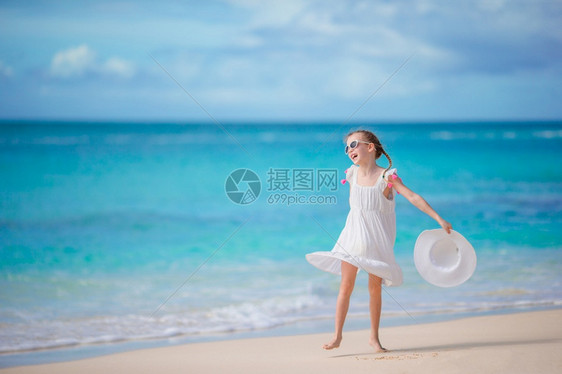 海岸线有趣的情感在海滩上穿着衣服的漂亮女孩快乐享受暑假背景蓝天和海中绿水在卡利比恩岛海边穿着洋装的漂亮女孩在海滩玩得开心图片
