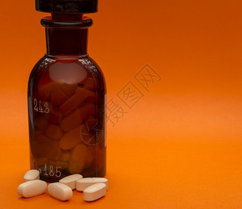 药品草本优雅的玻璃瓶装有药片的玻璃瓶和橙底皮上的香味空间玻璃瓶装有药片和香味空间图片