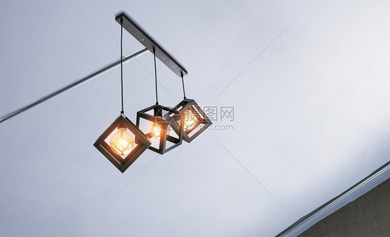活的建造绞刑在客厅内白色天花板上挂有电导管的现代三个金属笼套吊灯其低角视距图片