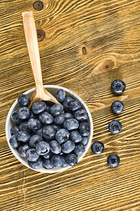 一张桌边的蓝莓夏季一张桌子上的蓝莓一张在木制桌上散布的成熟和美味果子照片一个餐桌上有生锈的木勺子团体麸质紫色的图片