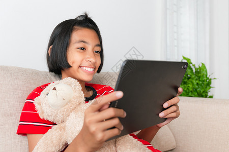 亚裔小女孩坐在沙发上Doll在她家里坐着时穿红色衬衫可爱的亚洲红色图片