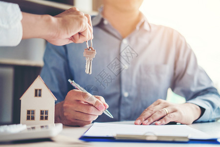 买支付方向客户提供房钥匙和签署协议合同的销售代理商保险住房概念图片