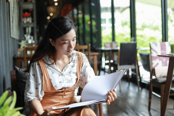亚洲裔女在咖啡店看书笑和快乐早晨随意的图片