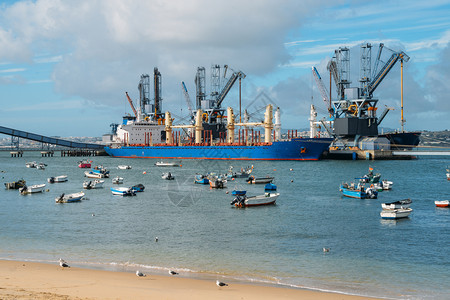 海岸油质的葡萄牙特拉法里亚的粮食衍生产品和油质的深水码头和筒仓在海滩附近有渔船葡萄牙特拉法里亚的粮食衍生产品和油质的深水码头和筒图片