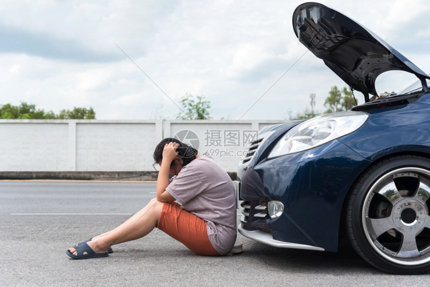 怀疑独自的在路边妇女因汽车引擎问题不快乐和沮丧地等待汽车机械工与发动机问题之间她因汽车发动机问题感到不高兴和沮丧的修理问题而感到图片