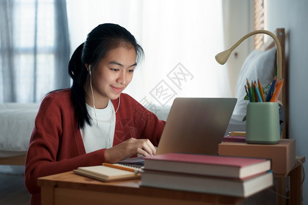 亚裔女孩在晚上坐卧室睡觉时学习在家上线校对PortnoyibleNationallifywn会议电脑互联网图片
