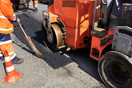 积极的压路机与道服务队安装沥青并修复路段压机和施工队在围栏路段的道上修复部分沥青地点碎石图片