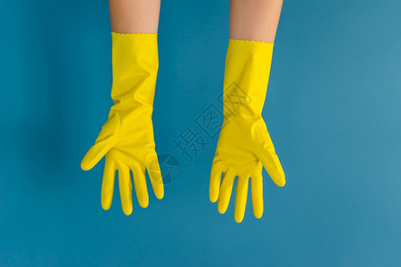 干净的新冠未知紧贴着身份不明的caucasian女孩的手她们举起双戴保护黄色橡胶手套用来在白天蓝墙背景进行清洁或消毒图片