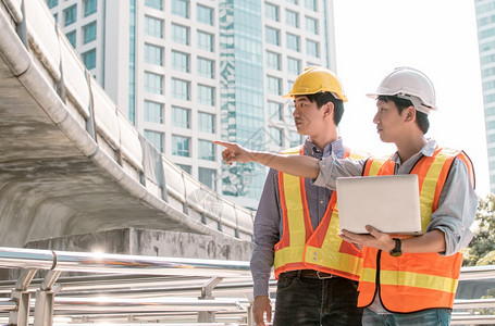 工人技术团队合作两名男工程师在建筑地谈论和使用笔记本电脑讨论项目时使用膝上型电脑图片