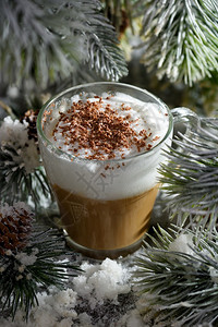 晚餐盛宴牛奶在雪覆盖的松树枝和雪中一杯大热咖啡加巧克力剃须还有巧克力刮胡屑图片
