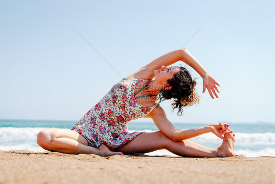 女士合十礼身夏天穿着衣服的年轻女子在海边滩做瑜伽在阳光明媚的白天图片