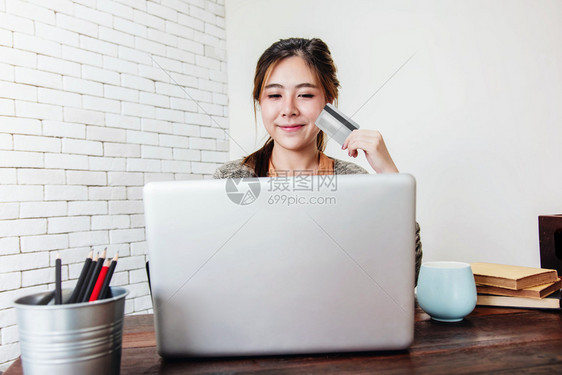 安全美丽微笑青年妇女通过信用卡和笔记本电脑在家中购物或付款幸福女通过网上购买产品图片