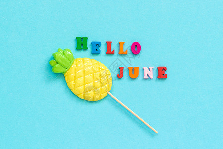 充满活力或者季节你好六月彩色文字菠萝棒糖在蓝纸背景上概念假期或创意顶视图模板贺卡明信片你好六月彩色文字明信片图片
