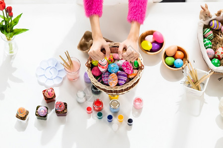 复活节概念紧握着戴兔子耳朵的手拿着篮子在白木桌底色背景上装满彩色复活节鸡蛋喜庆的手工制作节日图片