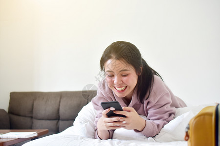 说谎拥有移动智能手机的年轻美容女躺在床上通过互联网社交络在线4g