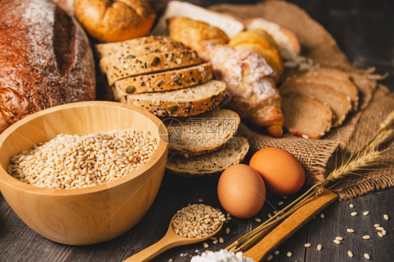 粮食小米不同种类的面包木质背景中的营养全麦面包厨房概念中的食物和面包店美味的早餐和膳食羊角面包图片
