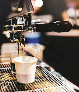 进入卡布奇诺一种浓缩咖啡机冲泡倒入店的玻璃杯中浓缩咖啡从机中倒出图片