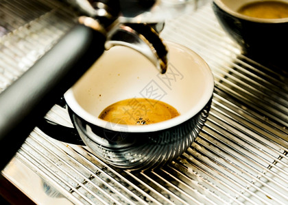 休息制造温暖的浓缩咖啡机冲泡倒入店的玻璃杯中浓缩咖啡从机中倒出图片