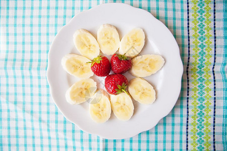 白盘子上的香蕉和草莓彩色餐巾纸白盘子上的香蕉和草莓以及彩色餐巾纸薄片烹饪白色的图片